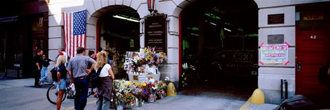 Framed Rear view of three people standing in front of a memorial at a fire station, New York City, New York State, USA Print