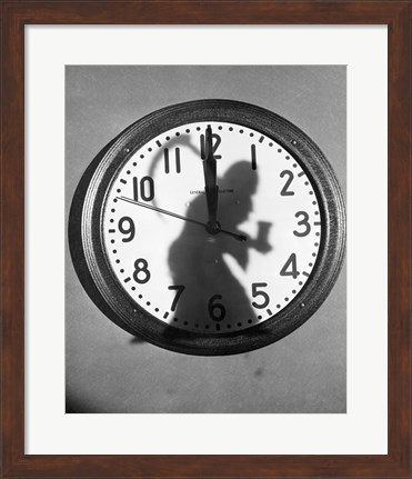 Framed Close-up of the shadow of a person carrying a scythe on a clock Print
