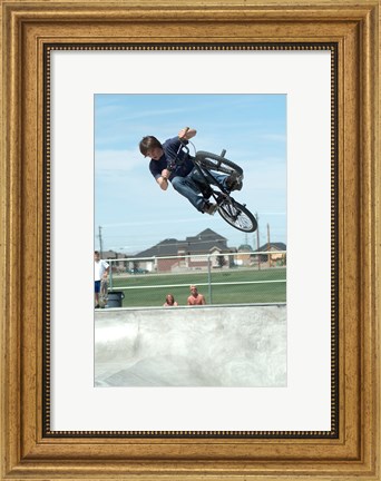 Framed Low angle view of a teenage boy performing a stunt on a bicycle over ramp Print