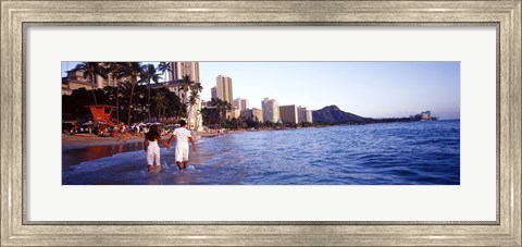 Framed Rear view of a couple wading on the beach, Waikiki Beach, Honolulu, Oahu, Hawaii, USA Print