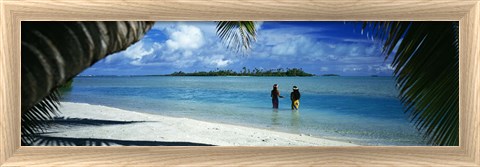 Panoramic Images Rear view of two native teenage girls in lagoon, framed by palm tree, Aitutaki, Cook Islands.