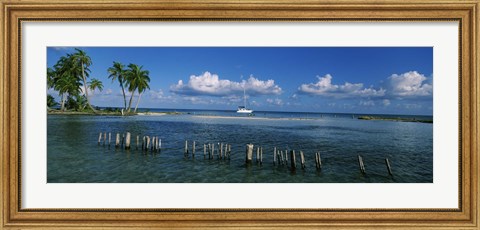 Framed Wooden posts in the sea with a boat in background, Laughing Bird Caye, Victoria Channel, Belize Print