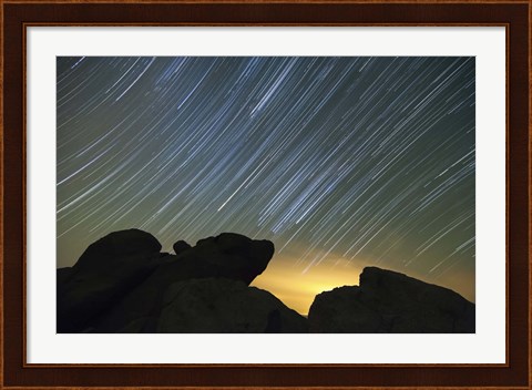 Framed Light pollution illuminates the sky and star tails above large boulders Print
