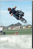 Low angle view of a teenage boy performing a stunt on a bicycle over ramp Fine Art Print