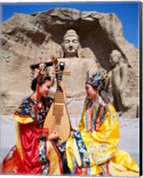 Two girls in traditional costumes in front of the Buddha Statue, China Fine Art Print
