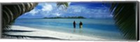 Rear view of two native teenage girls in lagoon, framed by palm tree, Aitutaki, Cook Islands. Fine Art Print
