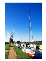Boats moored near a traditional windmill, Horsey Windpump, Horsey, Norfolk Broads, Norfolk, England Fine Art Print