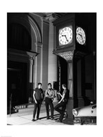 Young men standing below clock at night Fine Art Print