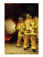 Rear view of three firefighters extinguishing a fire Fine Art Print