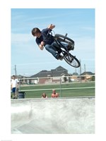 Low angle view of a teenage boy performing a stunt on a bicycle over ramp - various sizes