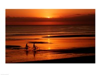 Silhouette of a young couple cycling on the beach Fine Art Print