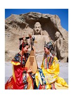 Two girls in traditional costumes in front of the Buddha Statue, China Fine Art Print