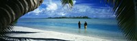 Rear view of two native teenage girls in lagoon, framed by palm tree, Aitutaki, Cook Islands. Fine Art Print