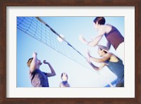 Low angle view of two young couples playing beach volleyball Fine Art Print