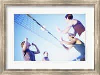 Low angle view of two young couples playing beach volleyball Fine Art Print