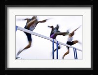 Low angle view of three men jumping over a hurdle Fine Art Print
