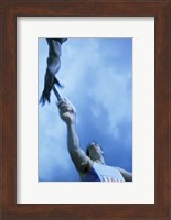 Low angle view of runners passing a baton in a relay race Fine Art Print