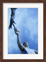 Low angle view of runners passing a baton in a relay race Fine Art Print
