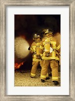 Rear view of three firefighters extinguishing a fire Fine Art Print