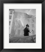 Firefighter pouring water on burning building, low angle view Fine Art Print