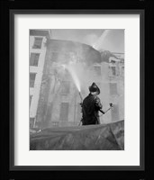 Firefighter pouring water on burning building, low angle view Fine Art Print