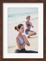 Young woman and a mid adult woman meditating on the beach Fine Art Print