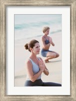 Young woman and a mid adult woman meditating on the beach Fine Art Print