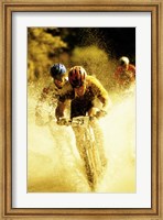 Young men riding bicycles through water Fine Art Print