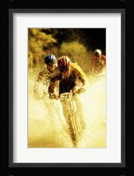 Young men riding bicycles through water Framed Print