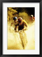 Young men riding bicycles through water Framed Print