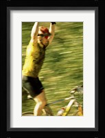 Young man sitting on a bicycle with his arms raised Framed Print