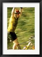 Young man sitting on a bicycle with his arms raised Framed Print