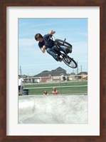 Low angle view of a teenage boy performing a stunt on a bicycle over ramp Fine Art Print