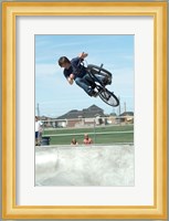 Low angle view of a teenage boy performing a stunt on a bicycle over ramp Fine Art Print