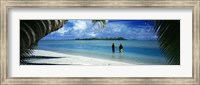 Rear view of two native teenage girls in lagoon, framed by palm tree, Aitutaki, Cook Islands. Fine Art Print