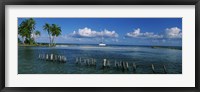 Wooden posts in the sea with a boat in background, Laughing Bird Caye, Victoria Channel, Belize Fine Art Print