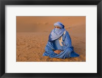 Veiled Tuareg man sitting cross-legged on the sand, Erg Chebbi, Morocco Fine Art Print