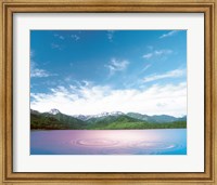 Pink light cast down on two rings in lavender water with deep blue sky and clouds over green mountains in distance Fine Art Print