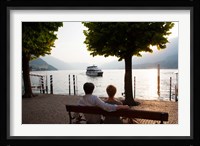 Couple sitting on bench and watching ferry approaching dock along the Lake Como, Bellagio, Province of Como, Lombardy, Italy Fine Art Print