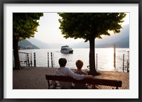 Couple sitting on bench and watching ferry approaching dock along the Lake Como, Bellagio, Province of Como, Lombardy, Italy Fine Art Print