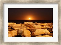 The moon rising behind rocks lit by a nearby fire in Miramar, Argentina Fine Art Print
