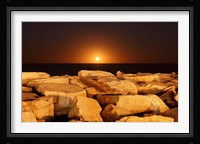 The moon rising behind rocks lit by a nearby fire in Miramar, Argentina Fine Art Print