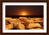 The moon rising behind rocks lit by a nearby fire in Miramar, Argentina Fine Art Print