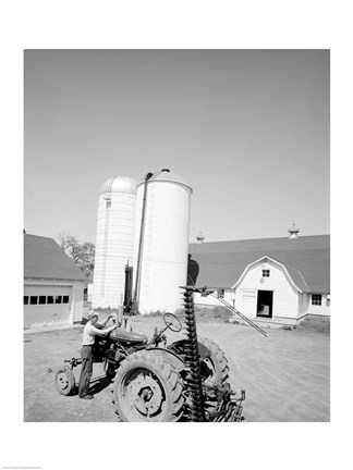 Framed USA, Farmer Working on Tractor, Agricultural Buildings in the Background Print