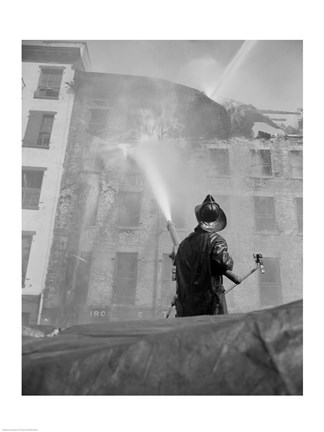 Framed Firefighter pouring water on burning building, low angle view Print