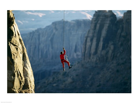 Framed Rear view of a man rappelling down a rock Print