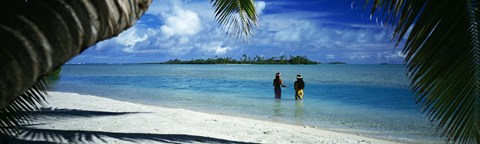 Framed Rear view of two native teenage girls in lagoon, framed by palm tree, Aitutaki, Cook Islands. Print