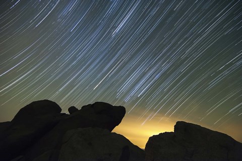 Framed Light pollution illuminates the sky and star tails above large boulders Print