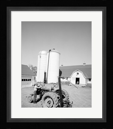 Framed USA, Farmer Working on Tractor, Agricultural Buildings in the Background Print