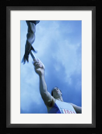 Framed Low angle view of runners passing a baton in a relay race Print